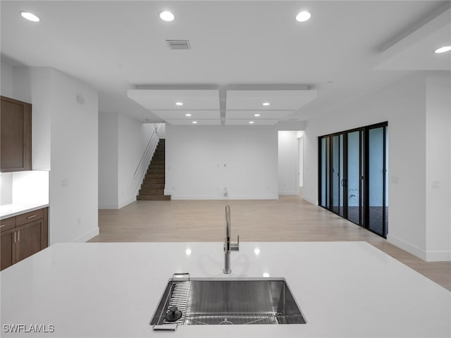 kitchen featuring sink, dark brown cabinetry, and light hardwood / wood-style floors