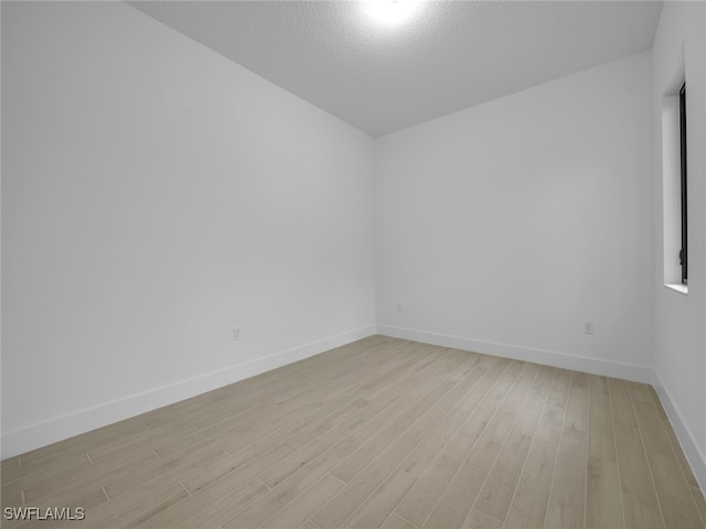 empty room featuring a textured ceiling and light hardwood / wood-style flooring