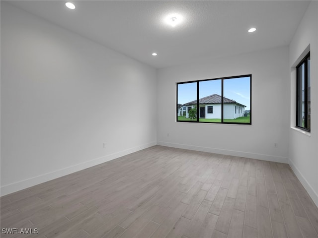 spare room featuring a textured ceiling and light hardwood / wood-style flooring