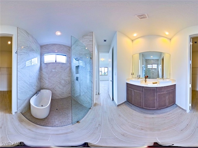 bathroom featuring tile walls, hardwood / wood-style floors, vanity, and a tile shower