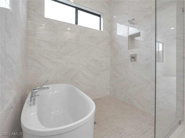 bathroom with tile walls, shower with separate bathtub, and sink