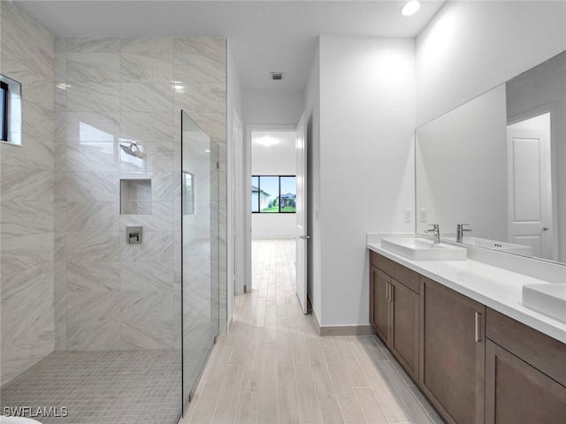 bathroom featuring vanity, hardwood / wood-style flooring, and tiled shower