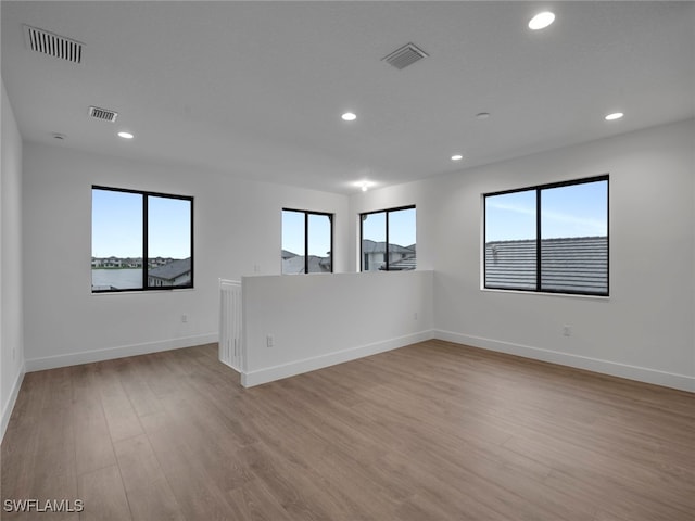 spare room with plenty of natural light and light hardwood / wood-style flooring