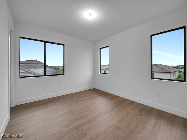 spare room with a textured ceiling and light hardwood / wood-style flooring