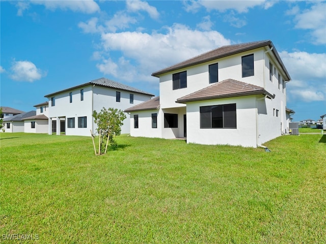 rear view of property featuring a lawn and central AC