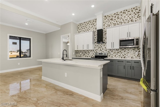 kitchen with ornamental molding, appliances with stainless steel finishes, a center island with sink, and white cabinets