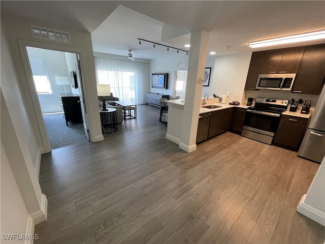 kitchen featuring stainless steel appliances, sink, kitchen peninsula, ceiling fan, and light hardwood / wood-style flooring