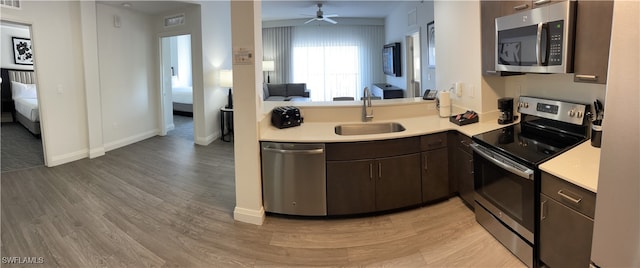 kitchen featuring stainless steel appliances, dark brown cabinets, sink, ceiling fan, and light hardwood / wood-style flooring