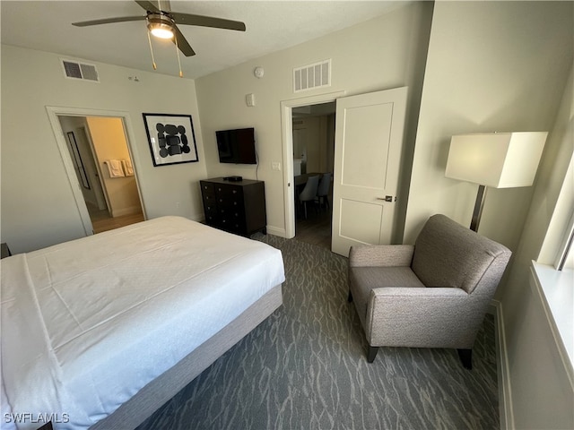 bedroom featuring dark colored carpet, ceiling fan, and connected bathroom