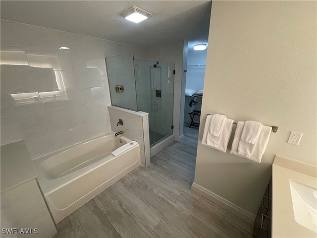 bathroom with hardwood / wood-style floors, a textured ceiling, shower with separate bathtub, and vanity