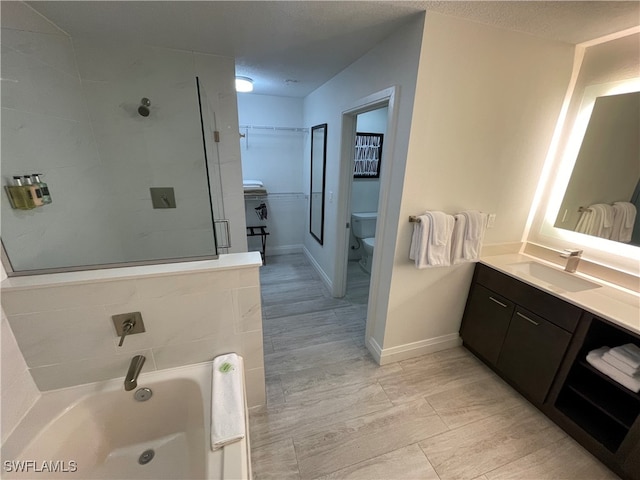 bathroom featuring a washtub, vanity, a textured ceiling, and toilet