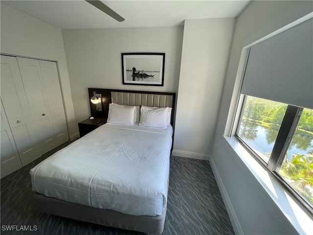 bedroom with ceiling fan, a closet, and dark carpet