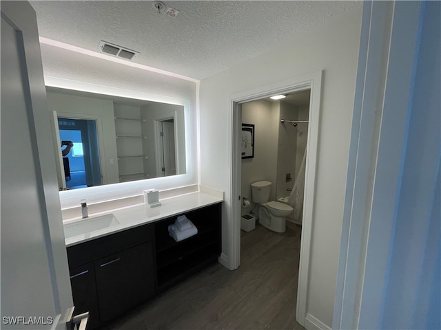 bathroom featuring toilet, vanity, wood-type flooring, and a textured ceiling