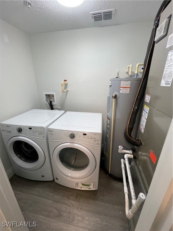 washroom with electric water heater, dark hardwood / wood-style flooring, a textured ceiling, and independent washer and dryer