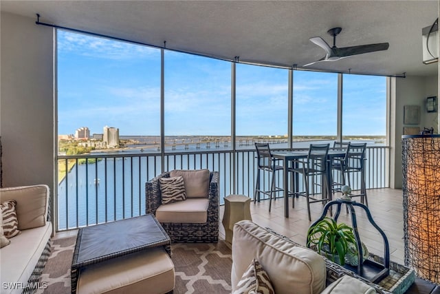 sunroom / solarium featuring ceiling fan and a water view