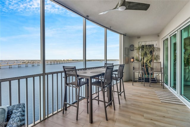 sunroom / solarium featuring ceiling fan and a water view