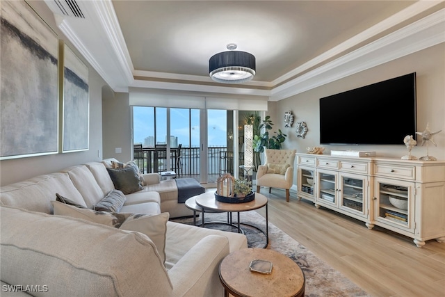 living room with a raised ceiling, light wood-type flooring, and ornamental molding