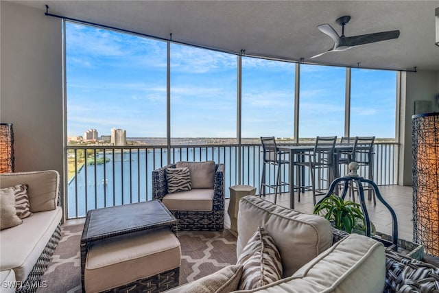 sunroom / solarium featuring ceiling fan and a water view