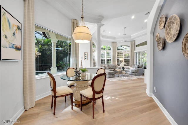 dining space with ornate columns, ornamental molding, and light hardwood / wood-style flooring