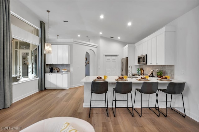 kitchen featuring kitchen peninsula, stainless steel appliances, pendant lighting, and white cabinetry