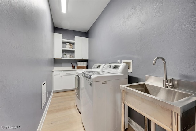 washroom with sink, independent washer and dryer, light hardwood / wood-style floors, and cabinets