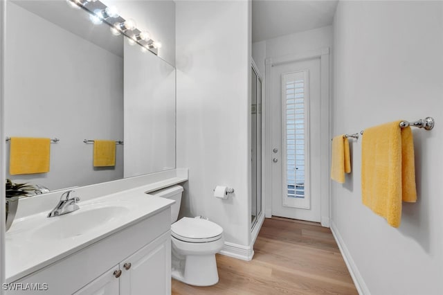 bathroom featuring vanity, toilet, hardwood / wood-style floors, and a shower with door