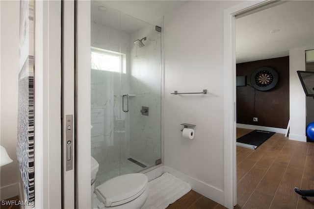 bathroom featuring hardwood / wood-style floors, toilet, and a shower with shower door