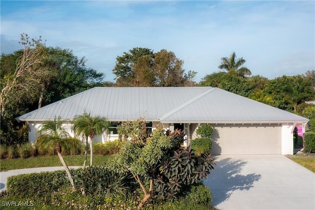 view of front facade featuring a garage, driveway, and metal roof