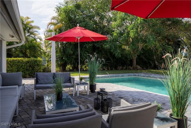 pool with an outdoor living space and a patio area