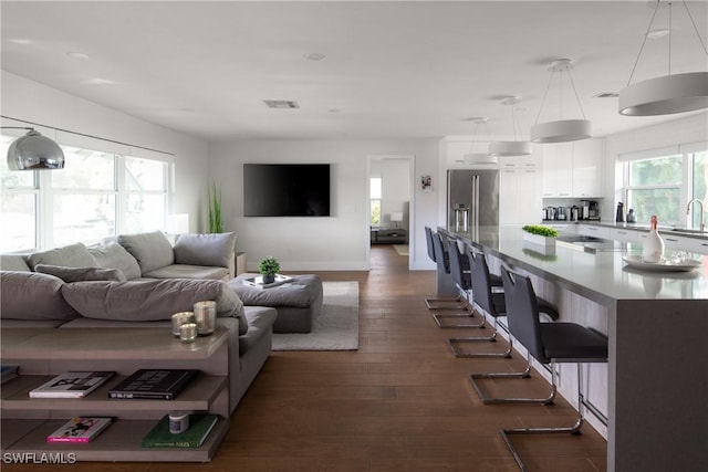 living area featuring visible vents, baseboards, and dark wood-style floors