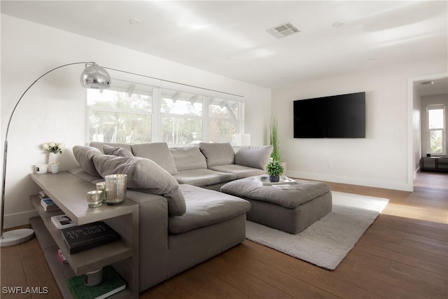 living area with baseboards, visible vents, and hardwood / wood-style floors