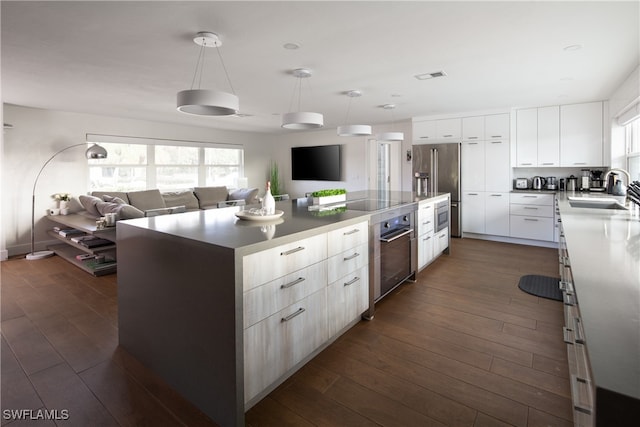 kitchen with dark hardwood / wood-style flooring, sink, a large island, white cabinetry, and high quality fridge