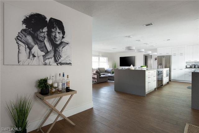 interior space featuring white cabinets, dark hardwood / wood-style floors, pendant lighting, and stainless steel appliances