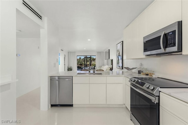 kitchen featuring kitchen peninsula, white cabinetry, sink, and appliances with stainless steel finishes