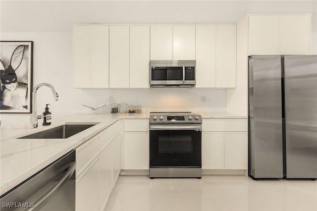 kitchen featuring a sink, light stone counters, appliances with stainless steel finishes, and white cabinetry