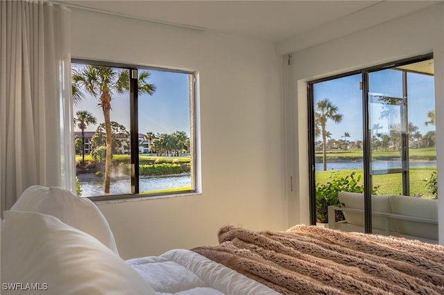 bedroom featuring access to exterior, multiple windows, and a water view