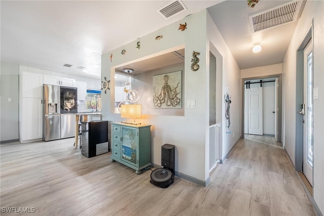 hallway featuring a barn door and light hardwood / wood-style floors