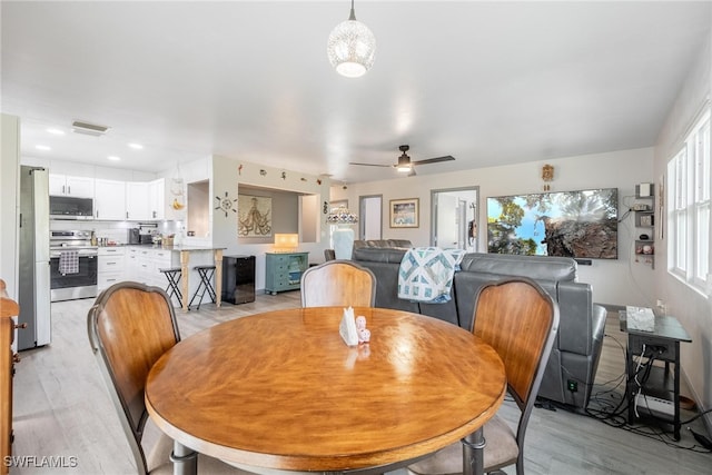 dining room featuring light wood-type flooring and ceiling fan with notable chandelier