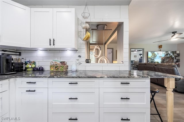 kitchen with decorative backsplash, white cabinetry, ceiling fan, and dark stone countertops