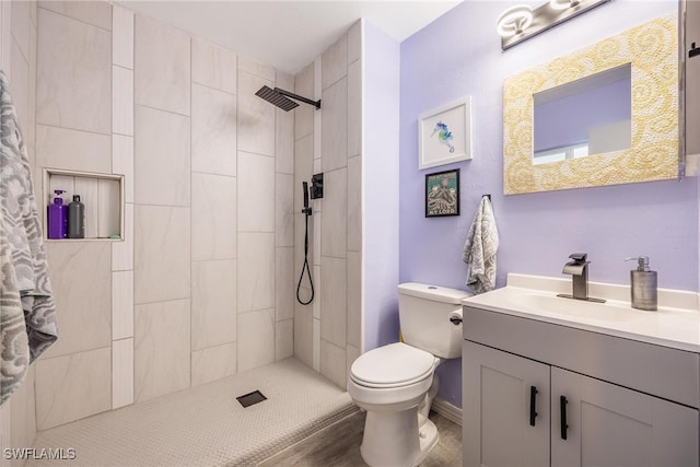 bathroom with tiled shower, vanity, and toilet