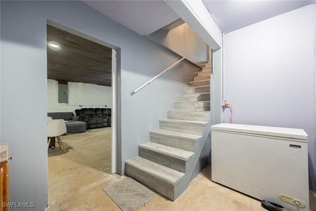 stairs featuring concrete flooring and electric panel