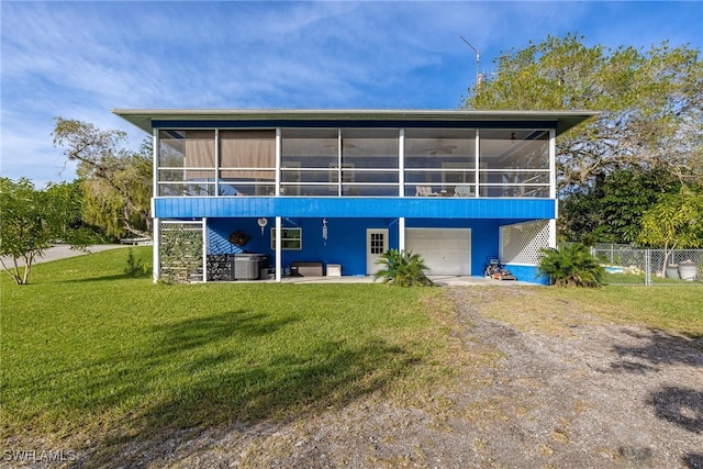 rear view of property featuring central AC unit, a garage, a lawn, and a sunroom