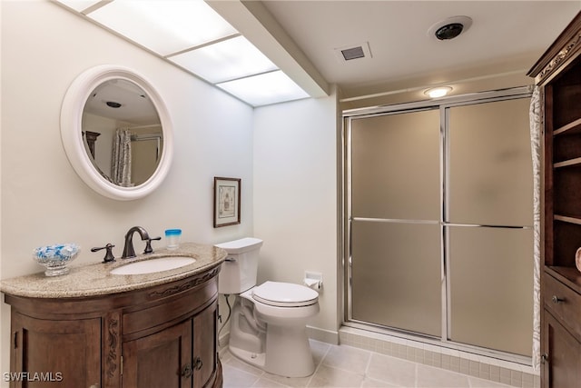 bathroom with tile patterned flooring, vanity, toilet, and a shower with shower door