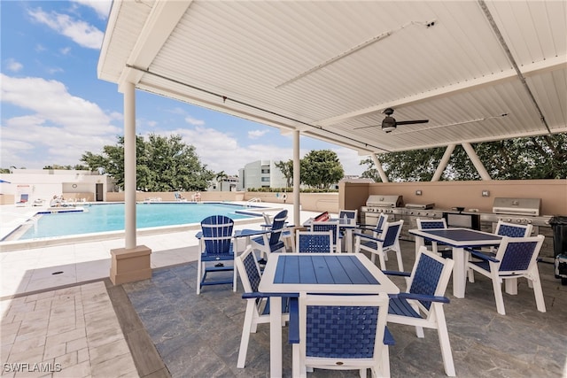 view of patio / terrace featuring an outdoor kitchen, a grill, ceiling fan, and a community pool