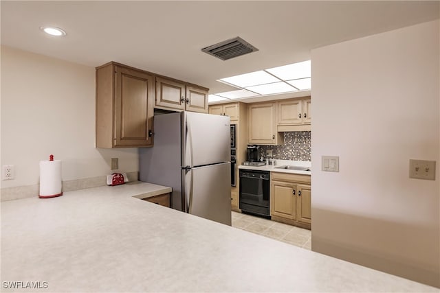 kitchen with sink, light tile patterned floors, black dishwasher, tasteful backsplash, and stainless steel refrigerator