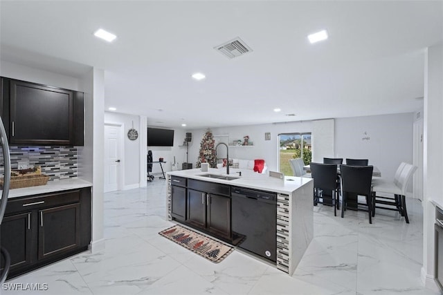 kitchen featuring dark brown cabinetry, black dishwasher, tasteful backsplash, sink, and a center island with sink