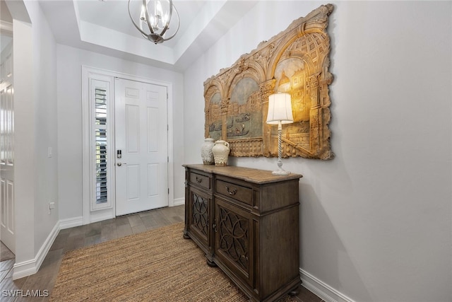 foyer entrance featuring an inviting chandelier, hardwood / wood-style flooring, and a raised ceiling