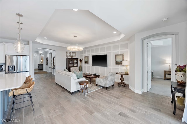 living room with light wood-type flooring and a tray ceiling