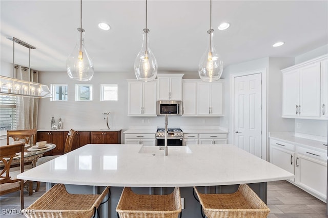 kitchen with pendant lighting, a center island with sink, white cabinets, and stainless steel appliances