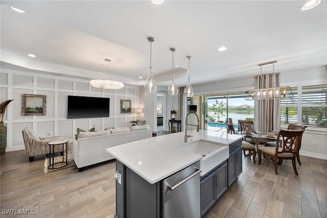 kitchen with pendant lighting, dishwasher, and an island with sink